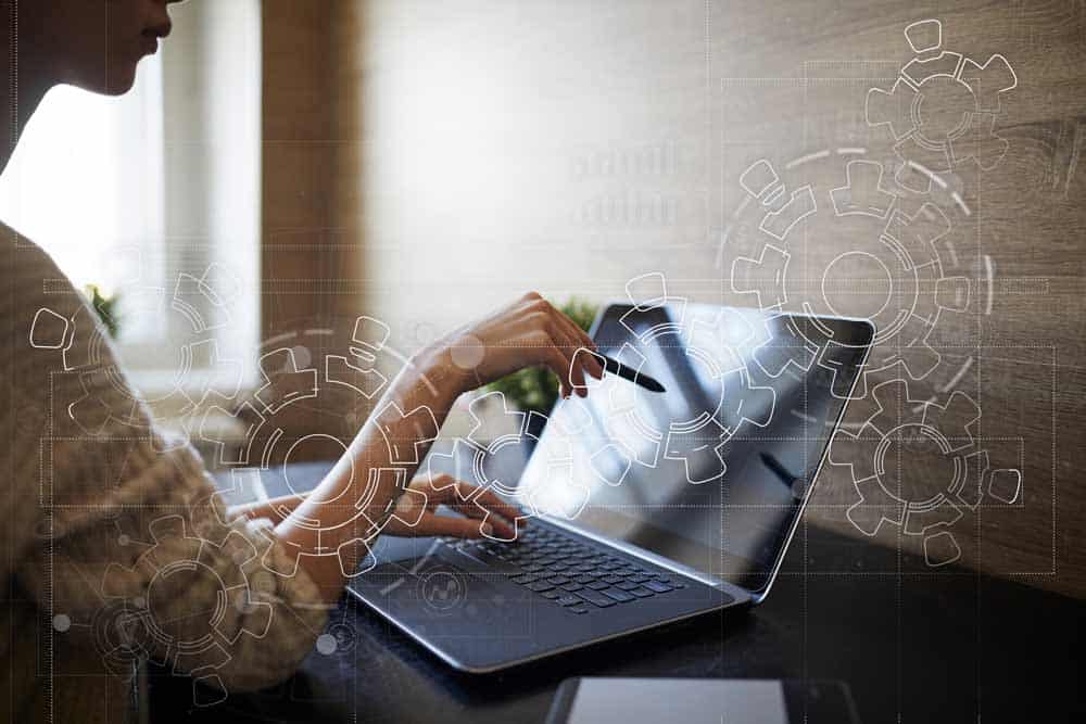 woman working on her laptop with cog sketch superimposed over the image